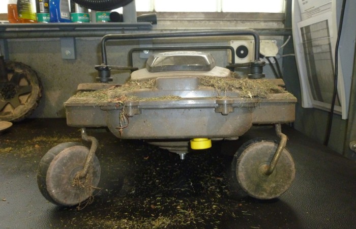 Der Rasenroboter vor der Reinigung. Ansicht von Vorne ohne Haube.