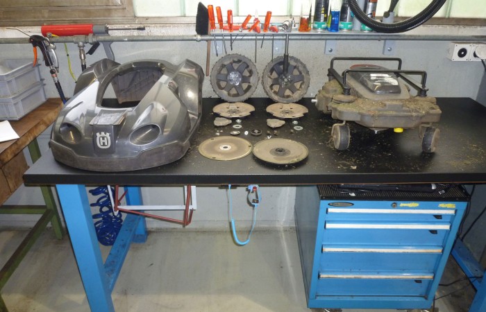 Zu Beginn des Services wird der Rasenroboter in seine Einzelteile zerlegt. Auf das Robotergehäuse rechts kommt ein Schutzbügel um Kratzer auf der Tastaturabdeckung auszuschliessen.