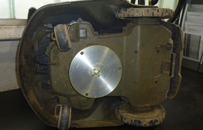 Ein Rasenroboter von unten vor der Reinigung.